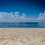 A tranquil beach scene with clear skies and gentle ocean waves, perfect for relaxation.