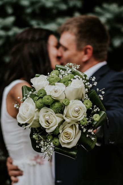 pexels-photo-948185-948185 A couple embracing with a focus on a white rose and green floral wedding bouquet.